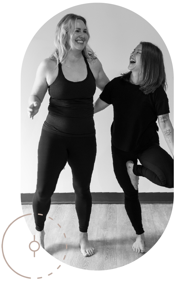 A student is laughing with Sarah while she smiles and obviously just came out of a yoga pose. 