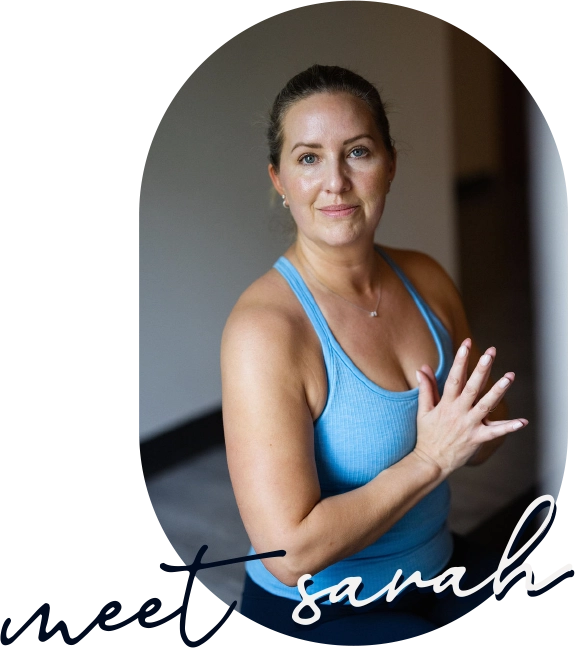 Portrait of yoga instructor Sarah Sandkuhl of Columbia, MO with hands at heart center facing the camera with a gentle smile. The image is overlaid with script text that reads "meet sarah".
